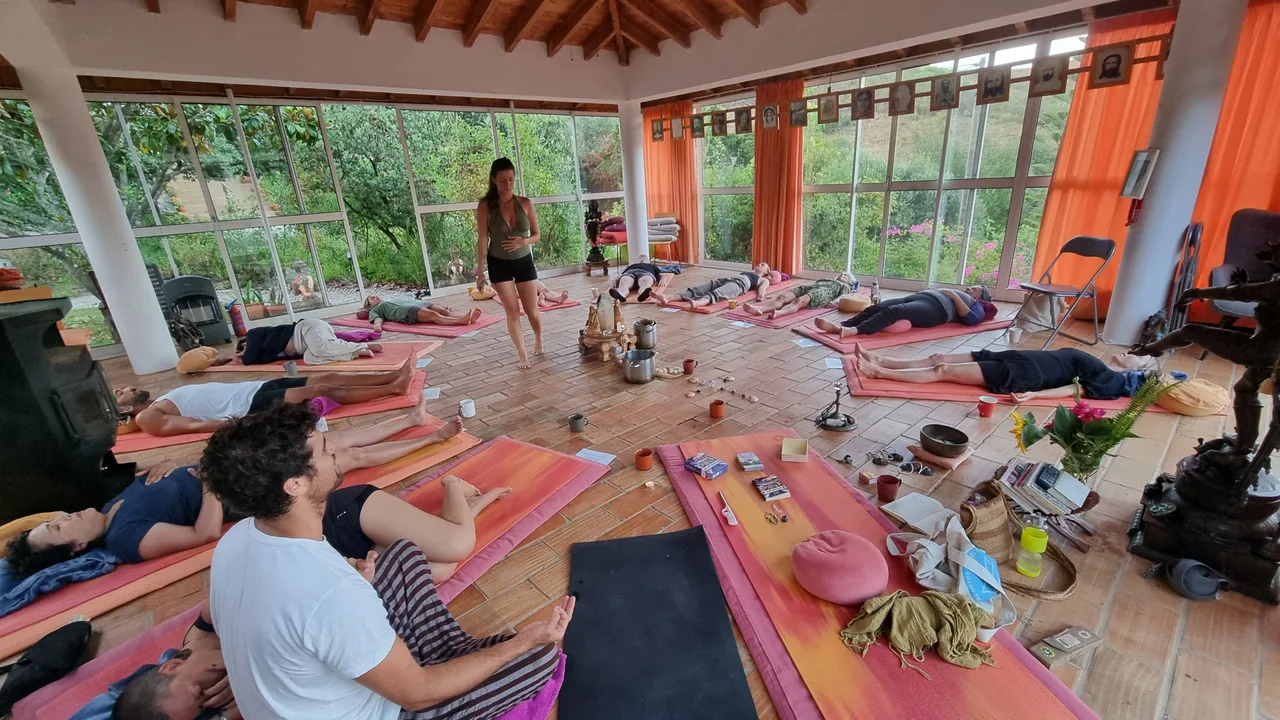 A group resting together on mats in a light-filled studio while Sofia holds space